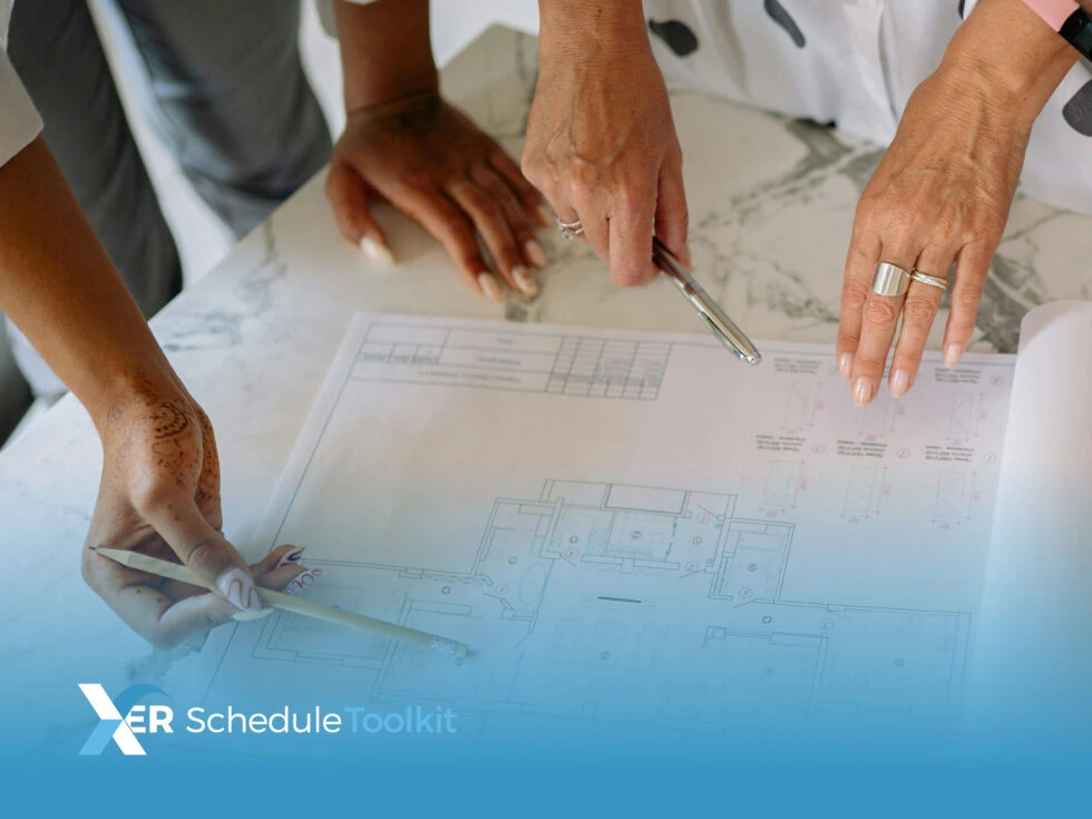 Close up of two womens' hands pointing at the blueprints to a project