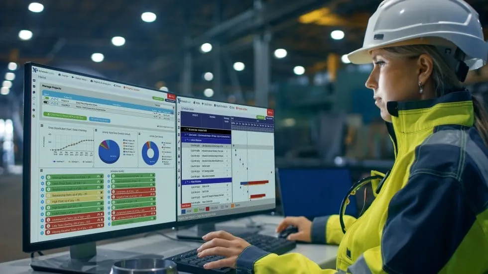 Girl in hardhat and hi-vis jacket, staring at the XER Schedule Toolkit in a warehouse